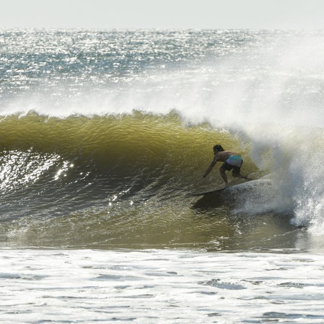 Longboarder cross-stepping on a long, peeling point break wave at El Zonte